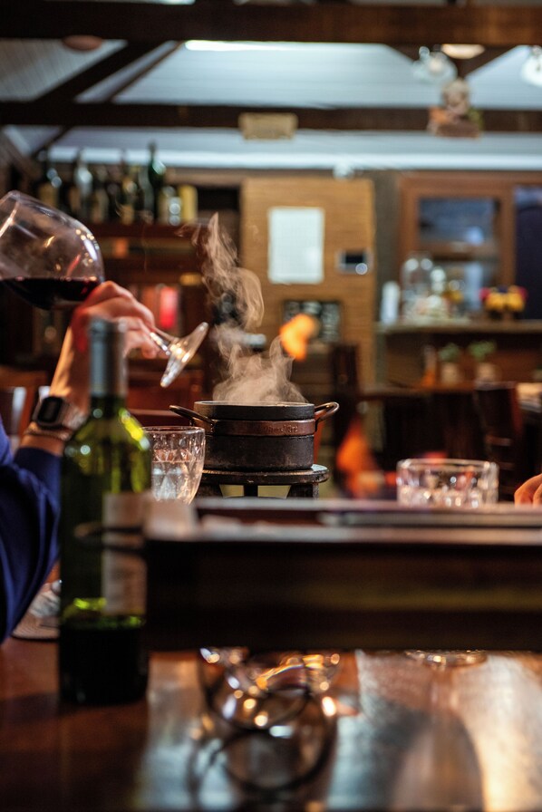 Eine Bar mit einer Person, die ein Getränk einschenkt, einer Weinflasche und Gläsern auf der Theke.