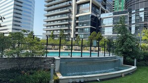 A modern building with a rooftop pool surrounded by greenery and a stone wall.