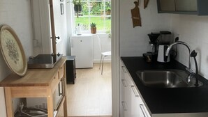 A kitchen with a sink, wooden table, and a view to a garden. - Husmandsvej 5 (Odder)