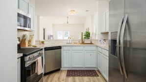 A modern kitchen with stainless steel appliances, light blue cabinets, and a central island. - Bluffton Lowcountry Casa Del Café/Private Driveway+Fence Yard (Bluffton)