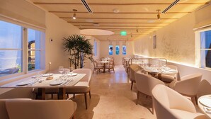 Un restaurante moderno con una amplia zona de comedor, techo de madera y grandes ventanales.