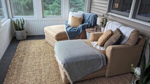A cozy room with a beige sofa, a patterned throw blanket, and a small side table with a lamp.