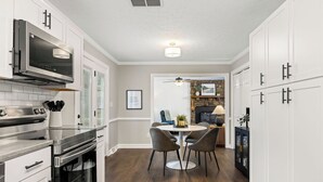 Een moderne keuken met witte kasten, roestvrijstalen apparatuur en een eethoek met een ronde tafel en stoelen.