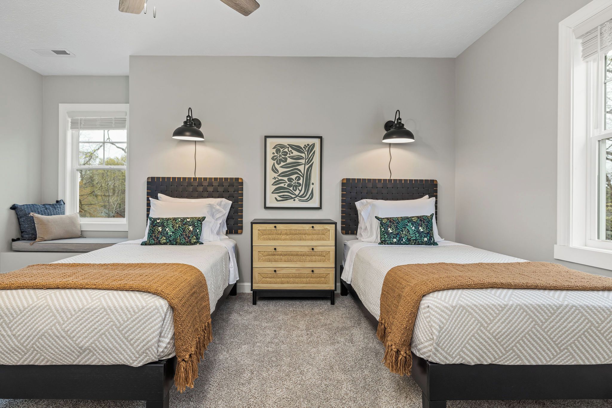 A bedroom with two beds, a nightstand, and a window.