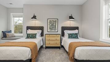 A bedroom with two beds, a nightstand, and a window.