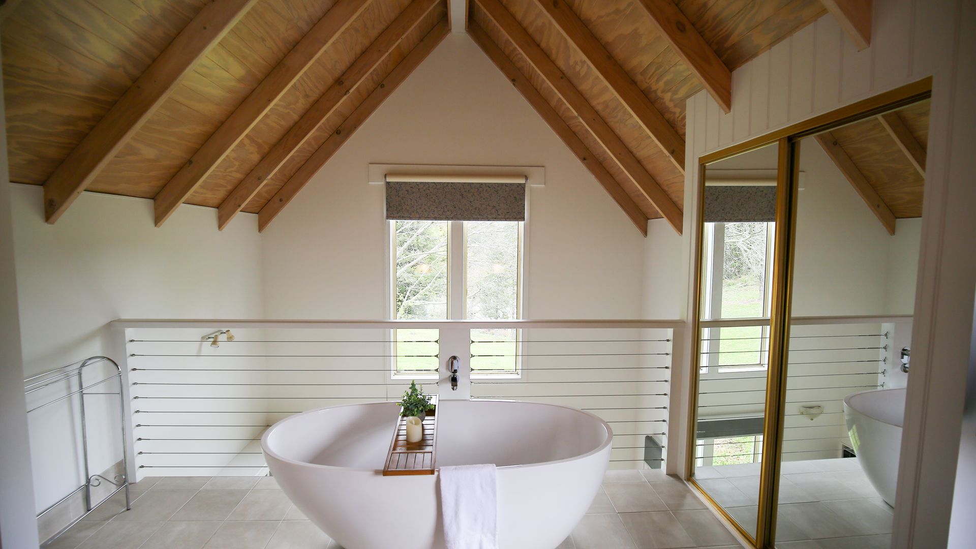 Een moderne badkamer met een vrijstaand bad, een raam en uitzicht op de omgeving.