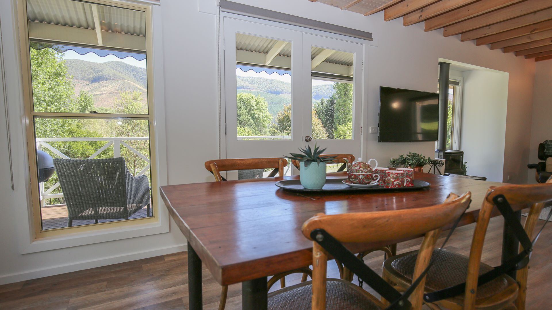 A dining area with a wooden table, chairs, and a view of the outdoors.