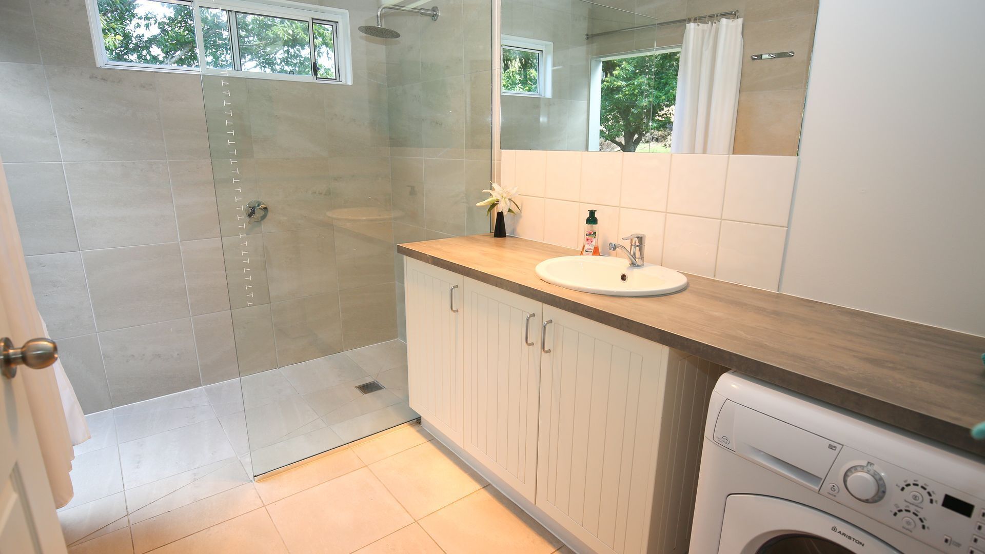 A bathroom with a shower, a sink, and a washing machine.