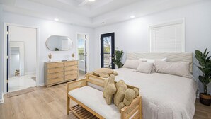 Ein Schlafzimmer mit Bett, Nachttisch, Kommode, Spiegel und Deckenventilator.