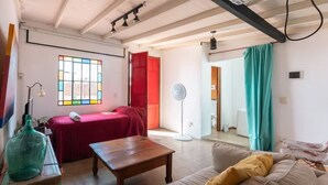 A room with a bed, a wooden table, a sofa, a large window, and a fan. - PH IN PALERMO SOHO WITH TWO SPECTACULAR TERRACES BBQ AND FAMILY ROOM (Buenos Aires)