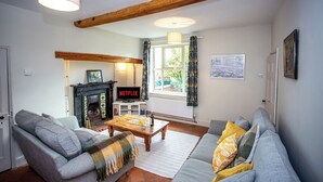 A living room with a fireplace, a sofa, a coffee table, and a television displaying 'Netflix'.