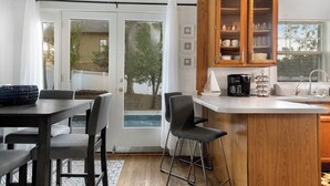 A kitchen with a wooden cabinet, a coffee maker, and a bar stool. - NEW! Southern Retreat w/Pool, BBQ & Game Room (Birmingham)
