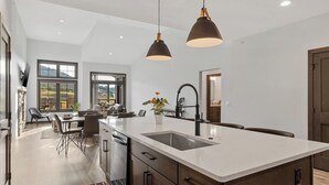 Een moderne keuken met een ruim eiland, hanglampen en uitzicht op de omgeving.
