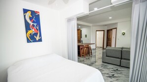 Una habitación de hotel con cama, un cuadro en la pared, un rincón de comedor y un sofá.
