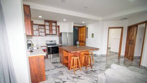 Una cocina moderna con armarios de madera, encimera de mármol y una isla central con taburetes.