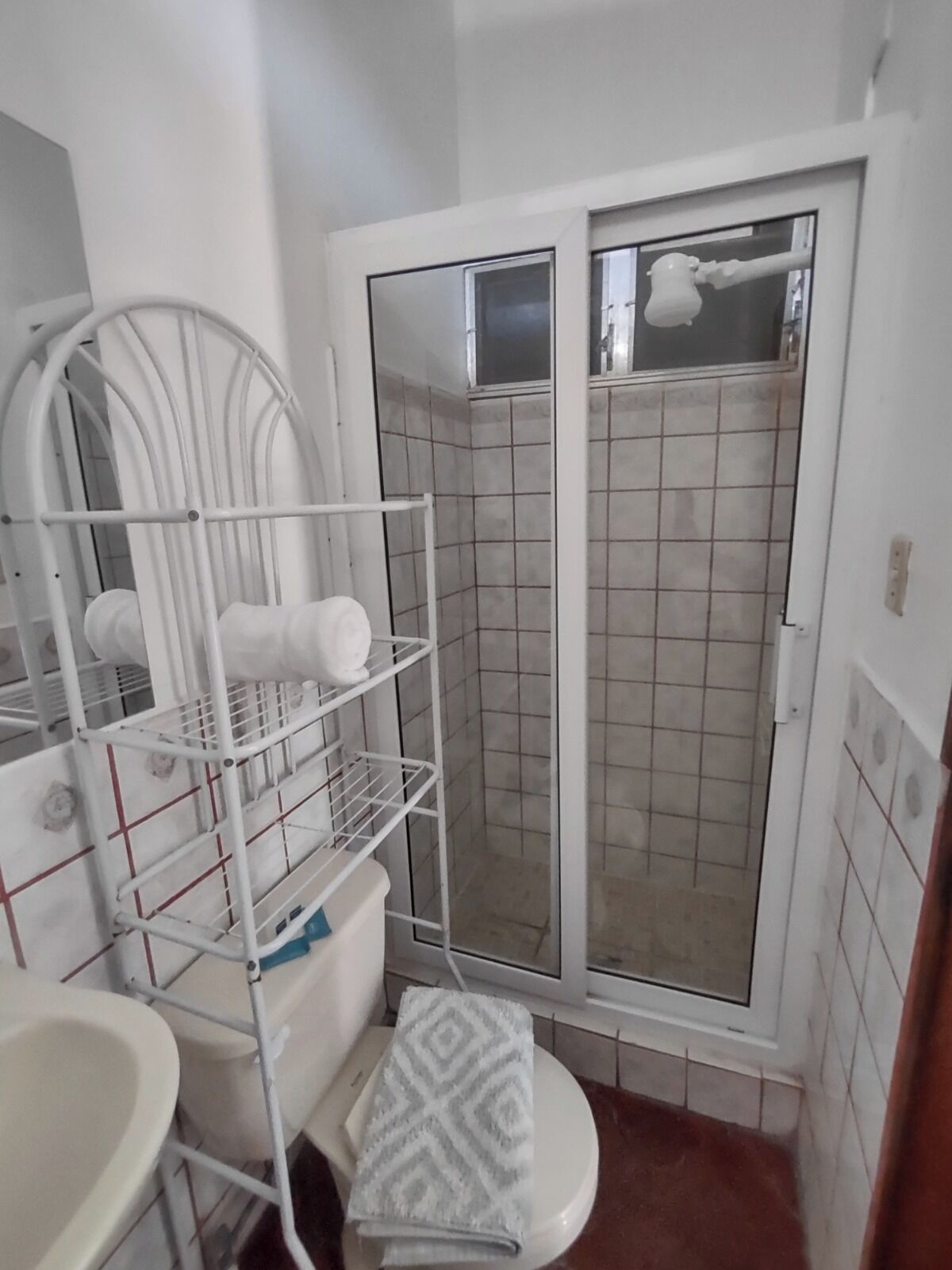A compact bathroom with a shower, a toilet, and a sink.