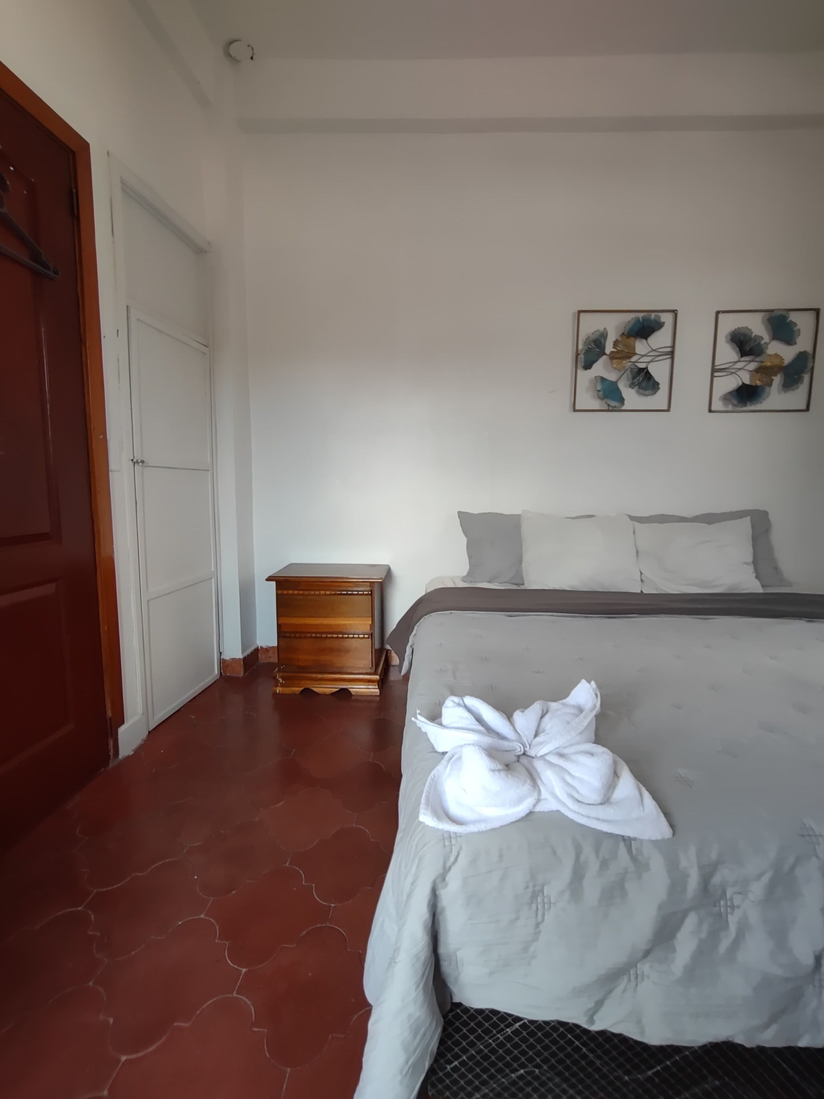 A bedroom with a bed, a wooden nightstand, and two wall art pieces.