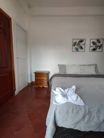 Un dormitorio con una cama, una mesita de noche de madera y dos obras de arte en la pared.