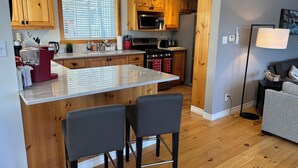 Una cocina moderna con armarios de madera, una isla grande y una zona de comedor con dos sillas.