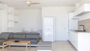 Una sala de estar moderna con un sofá gris, una mesa de centro de madera y un ventilador de techo.