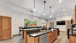 A modern kitchen with wooden cabinets, a stainless steel dishwasher, and pendant lighting.