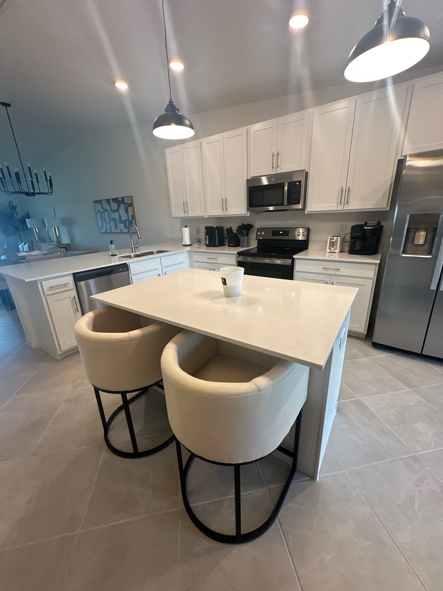 Una cocina moderna con armarios blancos, electrodomésticos de acero inoxidable e iluminación colgante.