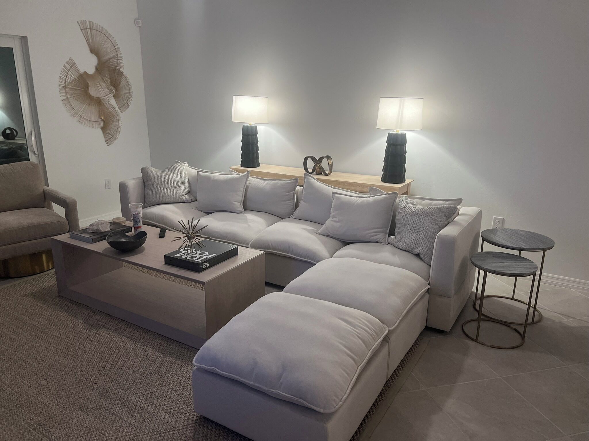 A modern living room with a sectional sofa, a coffee table, and two side tables with lamps.
