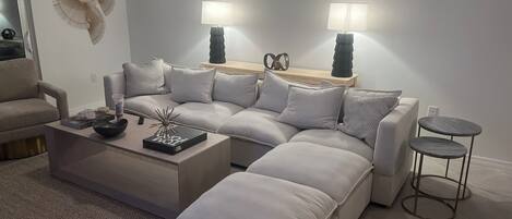 A modern living room with a sectional sofa, a coffee table, and two side tables with lamps.
