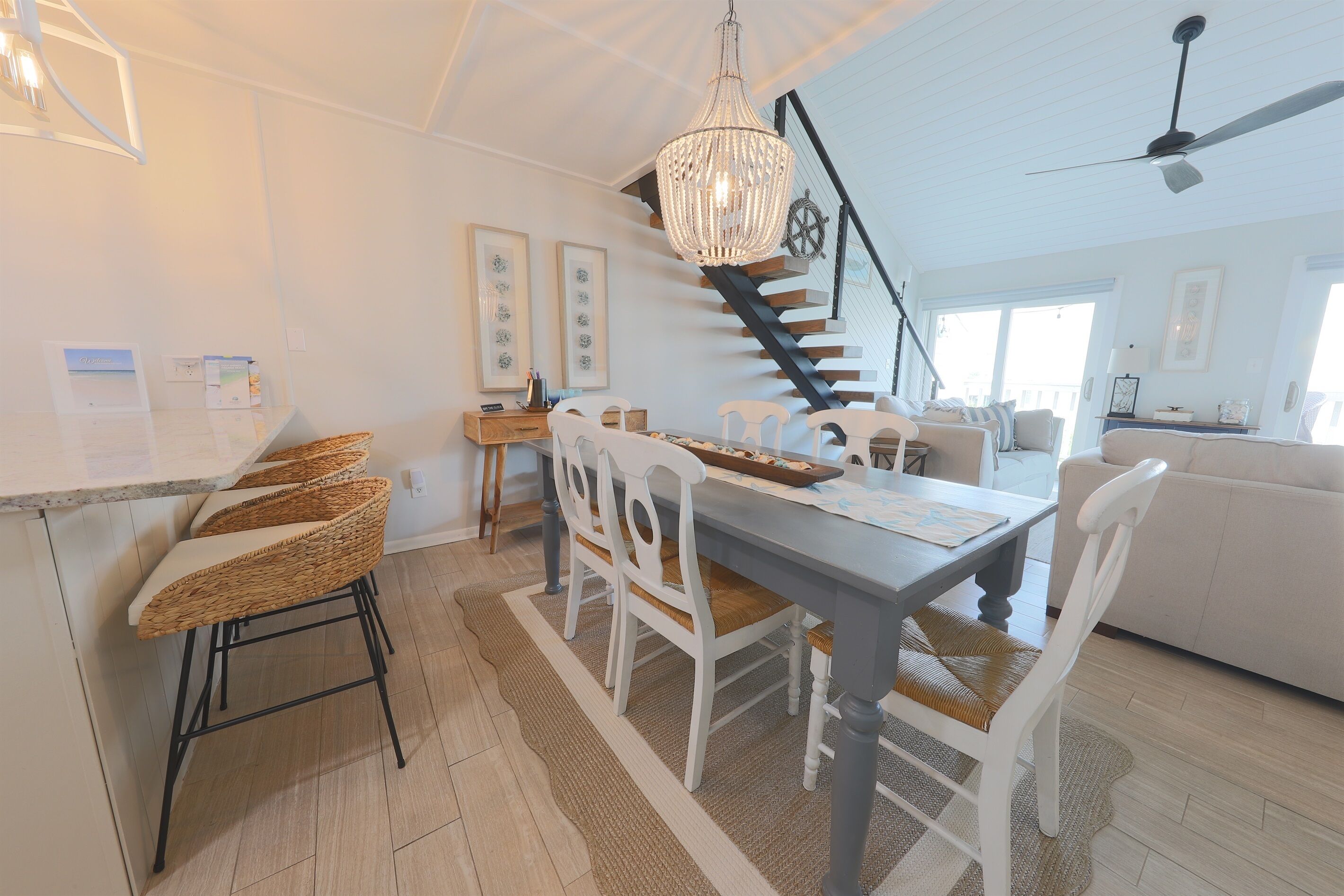 A spacious kitchen with a dining area, white furniture, and a staircase leading to a loft.