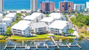 A coastal hotel with multiple white buildings, a marina with docked boats, and a view of the ocean.