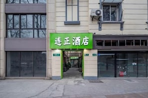 A hotel entrance with a green sign, a glass door, and a visible entrance.