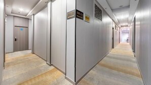 Een moderne hotelgang met een vloerkleed, een deur met de tekst 'Lobby' en richtingwijzers op de muren.
