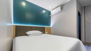 Een moderne hotelkamer met een groot bed, een muur in teal en een airconditioningsysteem.