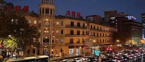 A busy urban street at night with a historic building featuring a prominent tower.