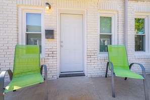 A building with a white door, two windows, and two green chairs in front. - Nearby Downtown! In Unit W&D + Pullout Sofa (Wichita)