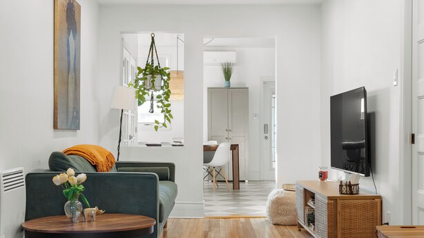 Ett modernt vardagsrum med en soffa, ett soffbord, en TV och en matplats med stolar och ett bord.