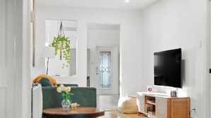 Ett modernt vardagsrum med en soffa, ett soffbord, en tv och en hängande växt.
