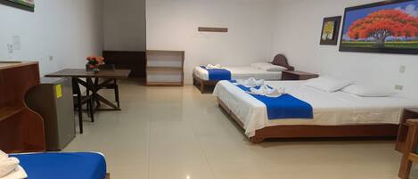 A hotel room with a bed, a desk, and a chair. There are two beds and a small table with a chair.