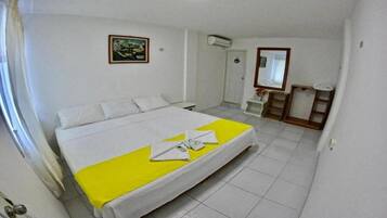 A hotel room with a bed, a bedside table, a mirror, and a painting on the wall.