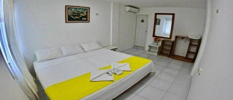 Una habitación de hotel con una cama, una mesita de noche, un espejo y un cuadro en la pared.