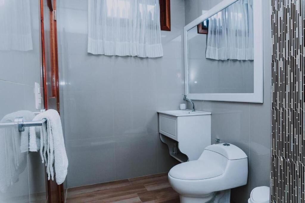 Un baño moderno con inodoro, lavamanos y espejo.
