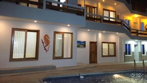 Un hotel de varios pisos con balcones, una piscina con una cisne y una decoración de caballito de mar en la pared.