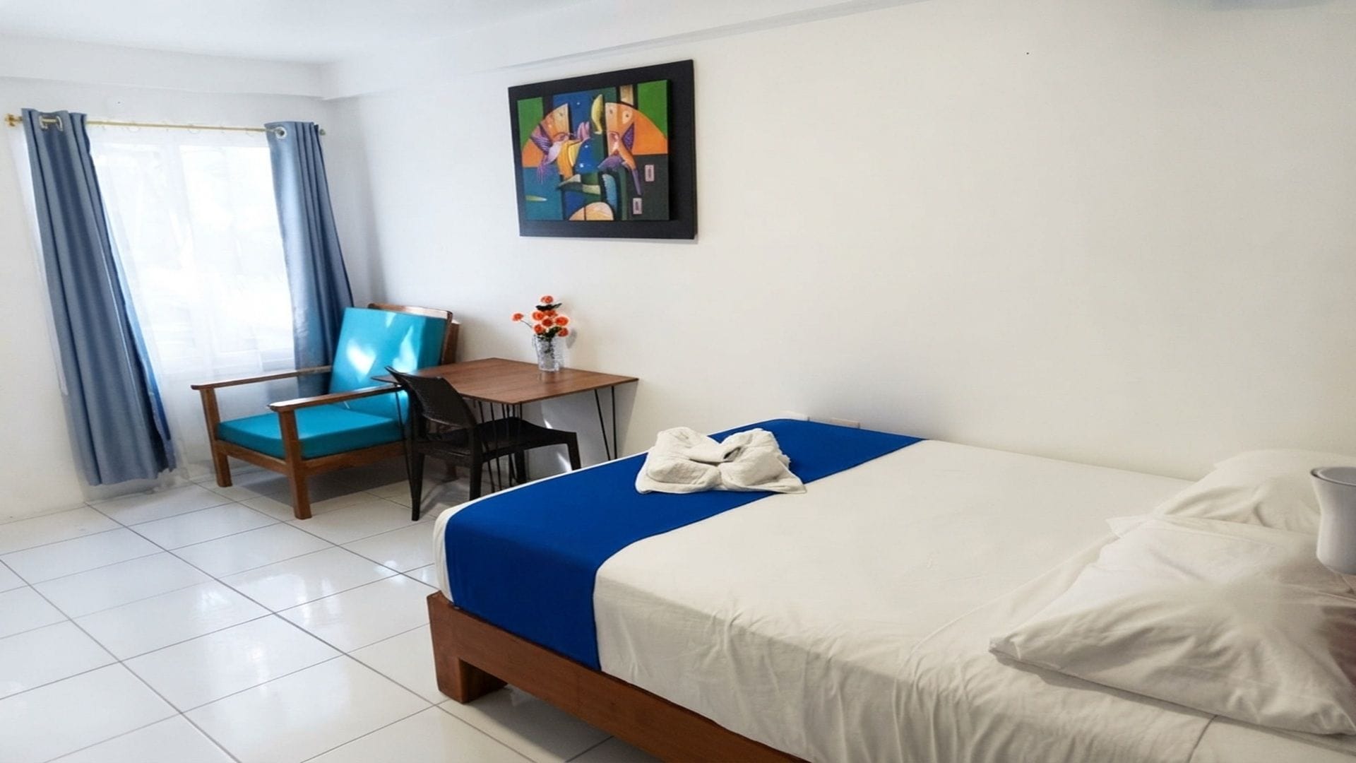 Ein Hotelzimmer mit einem Bett, einem Sessel, einem kleinen Tisch und einem Bild an der Wand.