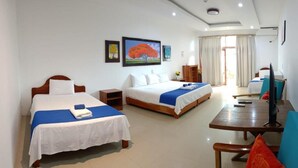 Una habitación de hotel con dos camas, un escritorio, una silla y un televisor.
