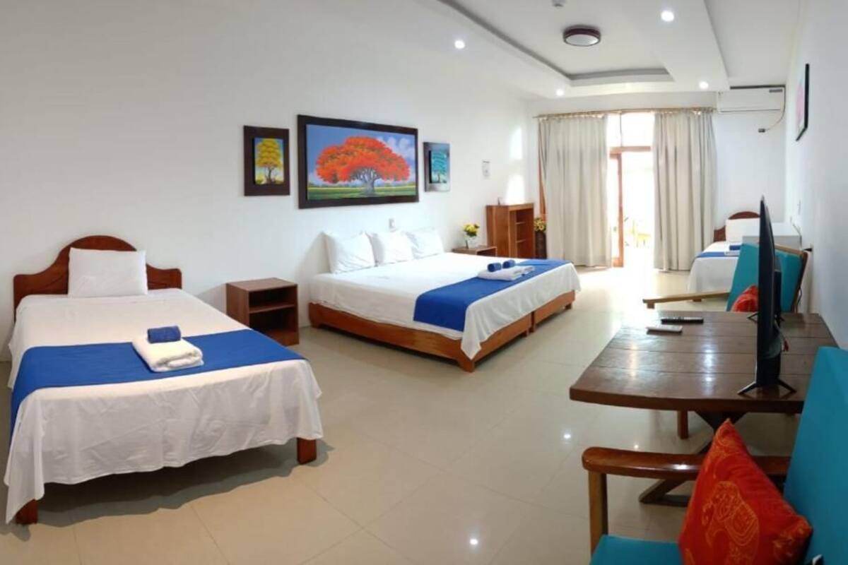 A hotel room with two beds, a desk, a chair, and a television.