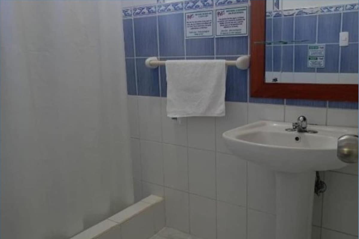 A bathroom with a white sink, a towel hanging on a rack, and blue and white tiled walls.