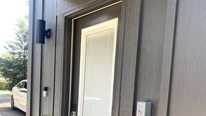 Une entrée moderne avec une porte métallique, un clavier pour ouvrir la porte et une petite boîte aux lettres.