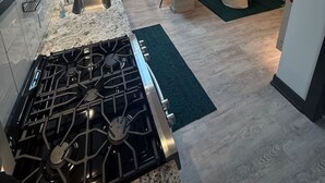 Une cuisine moderne équipée d’une cuisinière à gaz, d’un évier et d’un coin repas avec une table et des chaises.