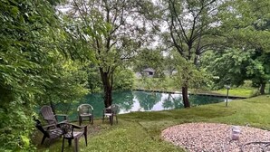 A grassy area with a pond, surrounded by trees and a few chairs. - Grand Park Modern Cubby 2BR/3BED/1BA/patio (Westfield)