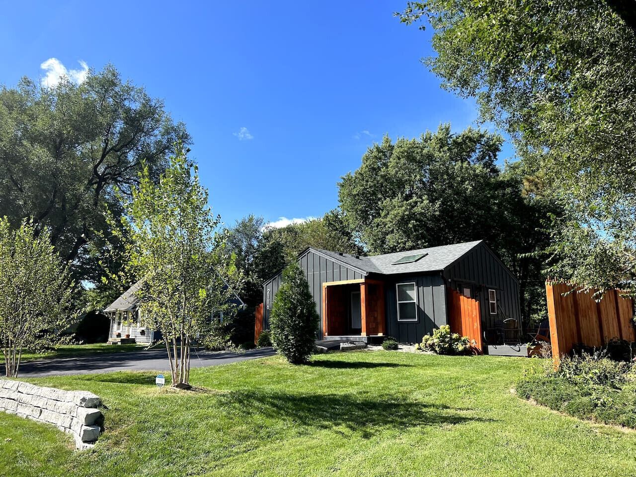 A modern two-story house with a dark exterior, a visible garage, and a well-maintained lawn.